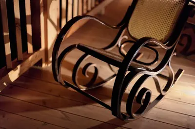 a black bench sitting on a wooden porch at Haus Himmelfahrt in Soprabolzano
