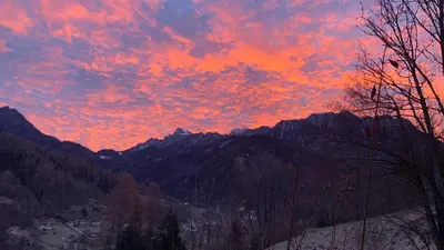 a sunset in the mountains with a red sky at Appartamento Casa Serena in Siror