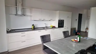 a kitchen with white cabinets and a table with chairs at Haus Bonell in Pianizza di Sopra