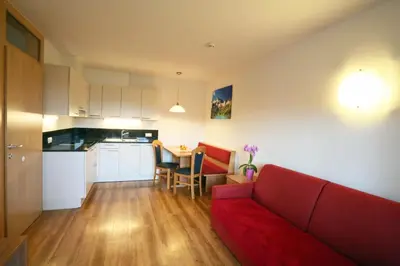 a living room with a red couch and a kitchen at Apartment Pichlerhof in San Lorenzo di Sebato