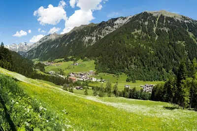 a green valley with a village in the mountains at Garni Bergland in Racines