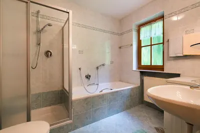 a bathroom with a shower and a tub and a sink at Garni Bergland in Racines