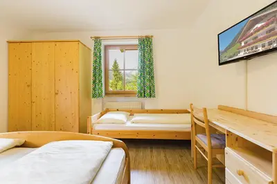 a room with three beds and a television in it at Garni Bergland in Racines