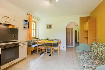 a kitchen and living room with a table and a couch at Garni Bergland in Racines