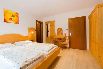 a bedroom with a bed and a desk in it at Garni Bergland in Racines