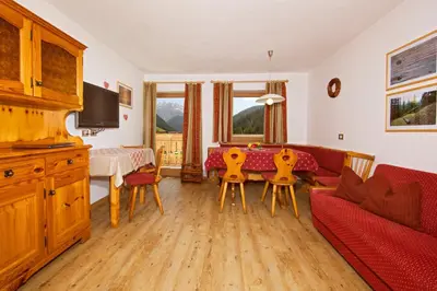a living room with a couch and a table and chairs at Appartamento Puez in Selva di Val Gardena