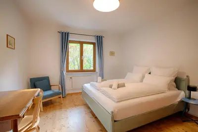 a bedroom with a bed and a table and a window at Apartment Hofgarten - Alpstay in Naturno