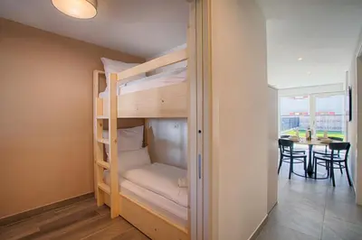 a bedroom with bunk beds in a room with a table at Apartment Lavendel - Alpstay in Naturno