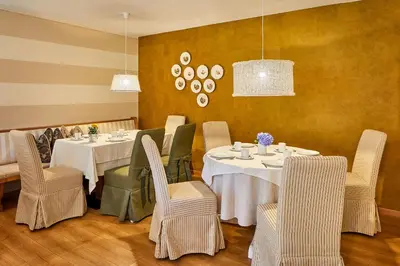 a dining room with two tables and chairs and lights at Garni Karin in Corvara in Badia