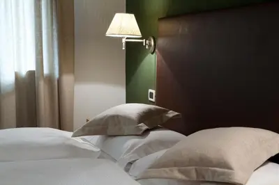 a bedroom with a bed with white pillows and a lamp at Garni Karin in Corvara in Badia