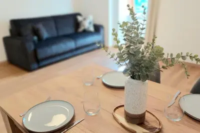 a wooden table with plates and a vase with flowers at Renovated flat close to the centre in Merano