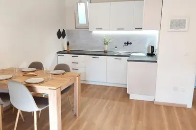 a kitchen with a wooden table and white cabinets at Renovated flat close to the centre in Merano