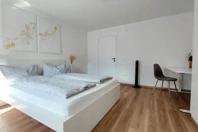 a white bedroom with a white bed and a chair at Renovated flat close to the centre in Merano