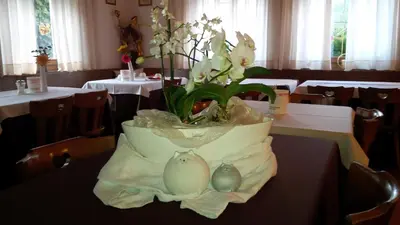 a vase of flowers on a table in a restaurant at Aparthotel Pichler in Colle Isarco