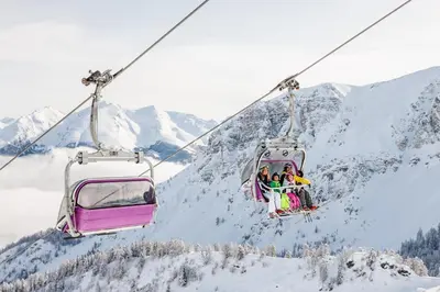 a group of people riding a ski lift in the snow at Aparthotel Pichler in Colle Isarco