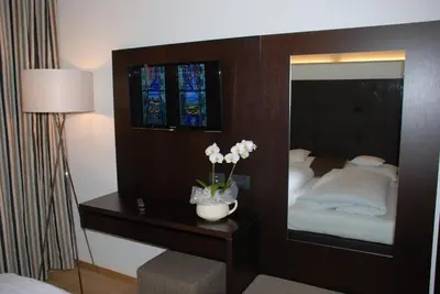 a bedroom with a mirror and a table with flowers at Aparthotel Pichler in Colle Isarco