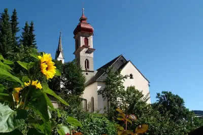 a church with a sunflower in front of it at Aparthotel Pichler in Colle Isarco