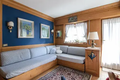 a living room with a couch and a window at Splendido appartamento a due passi dal centro con terrazza e garage in Cortina dʼAmpezzo