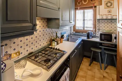a kitchen with a stove top oven next to a sink at Splendido appartamento a due passi dal centro con terrazza e garage in Cortina dʼAmpezzo