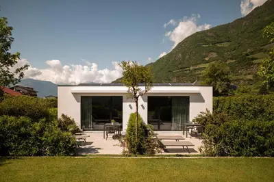 a white house with mountains in the background at Agriturismo Insolito in Terlano
