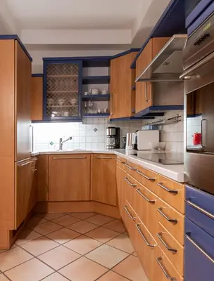 a large kitchen with wooden cabinets and blue accents at Apartment Perwanger in Appiano sulla Strada del Vino