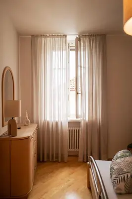 a bedroom with a bed and a window with curtains at Apartment Perwanger in Appiano sulla Strada del Vino