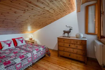 a bedroom with a bed and a wooden ceiling at Ciasa de Sèn Jan in Pozza di Fassa