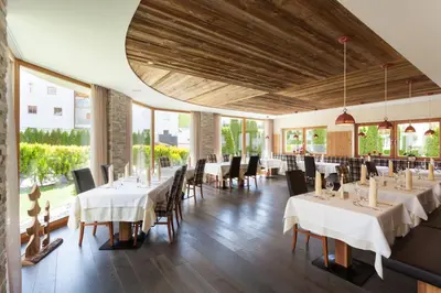 a restaurant with tables and chairs and large windows at Hotel Sonnenhof in Castelrotto