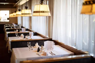 a row of tables in a restaurant with chandeliers at Hotel Sonnenhof in Castelrotto