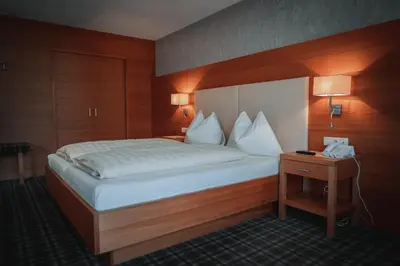 a bedroom with a bed and a nightstand with a phone at Hotel Sonnenhof in Castelrotto