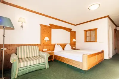 a bedroom with a bed and a chair at Hotel Sonnenhof in Castelrotto