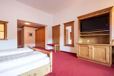 a bedroom with two beds and a flat screen tv at Hotel Sonnenhof in Castelrotto