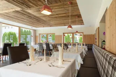 a restaurant with white tables and chairs and windows at Hotel Sonnenhof in Castelrotto