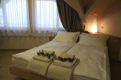 a bedroom with a bed with white sheets and flowers on it at Agriturismo Casa Preti in Revò