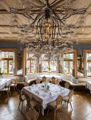 a dining room with white tables and a chandelier at Hotel Ostaria Posta in San Martino in Badia