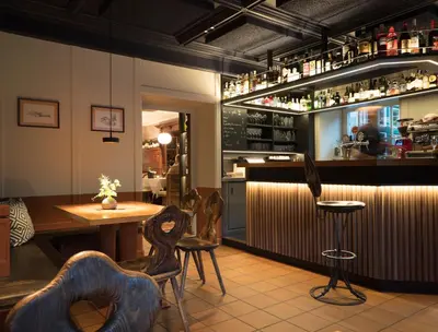 a restaurant with a bar with chairs and a table at Hotel Ostaria Posta in San Martino in Badia
