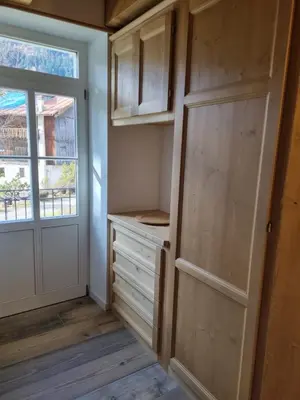 a closet with wooden cabinets and a door and a window at Appartamento Vale e Schena Cortina 4 posti letto in San Vito di Cadore