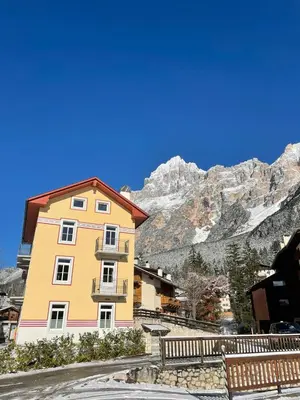 a yellow building in front of a mountain at Appartamento Vale e Schena Cortina 4 posti letto in San Vito di Cadore