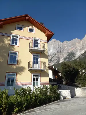 a yellow building with a balcony in front of a mountain at Appartamento Vale e Schena Cortina 4 posti letto in San Vito di Cadore