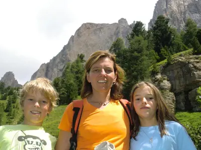 a woman and two children posing for a picture in front of mountains at Apartment Welscher in Nova Levante
