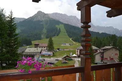 a view of a mountain from a balcony with flowers at Villa Tamion in Vigo di Fassa