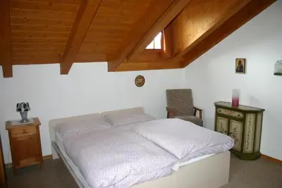 a bedroom with a white bed and a chair at Villa Tamion in Vigo di Fassa