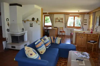a living room with a blue couch and a kitchen at Villa Tamion in Vigo di Fassa