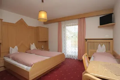 a bedroom with two beds and a television in it at Pension Peintner in Gais