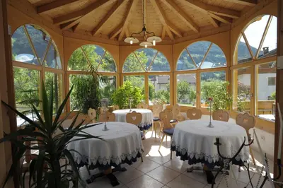 a room with two tables and chairs and windows at Pension Peintner in Gais