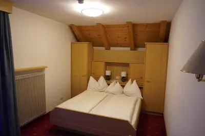 a bedroom with a bed with white sheets and pillows at Pension Peintner in Gais