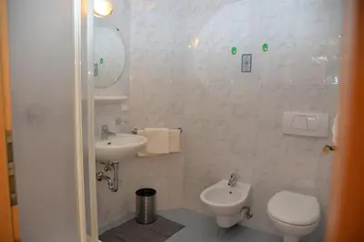 a white bathroom with a toilet and a sink at Unterwirtshof in Nova Ponente