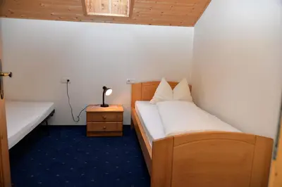 a small room with two beds and a night stand at Unterwirtshof in Nova Ponente