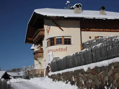 a building with a fence in the snow at Unterwirtshof in Nova Ponente