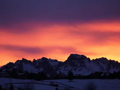 a sunset over a mountain range with snow at Unterwirtshof in Nova Ponente